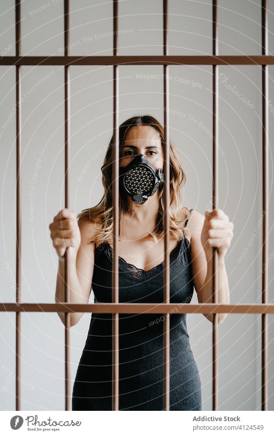 Woman in respirator mask behind bars woman fence confinement isolation covid coronavirus concept prevent prison lock protect female covid 19 covid19 pandemic