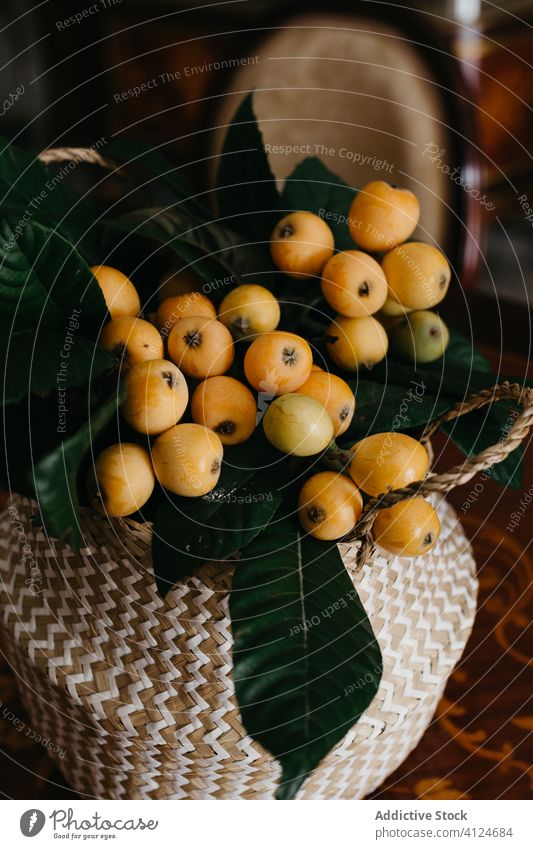 Wicker basket with nispero fruits in classy dining room loquat green leaf wicker retro table vintage ornament desk ingredient elegant old fashioned interior
