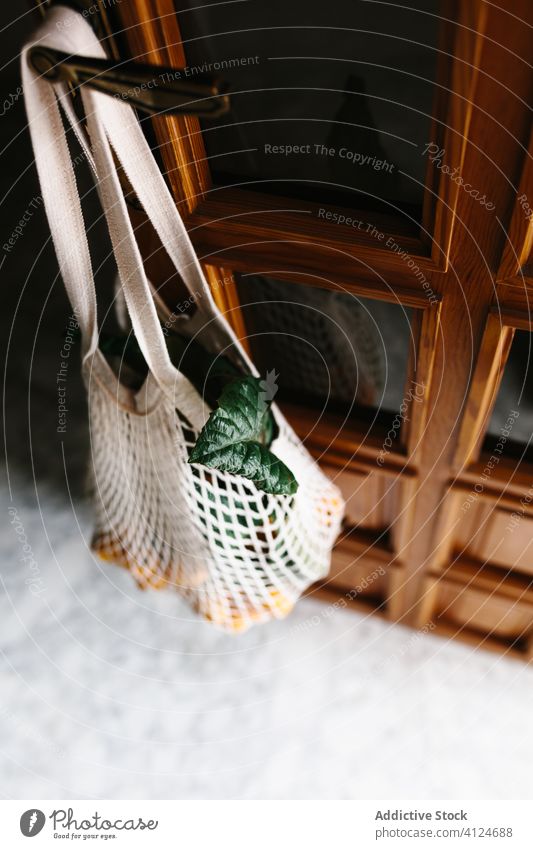 String shopping bag with nispero fruits hanging on doorknob eco friendly string loquat cotton sack room dark light fresh delicious tasty yummy natural vitamin