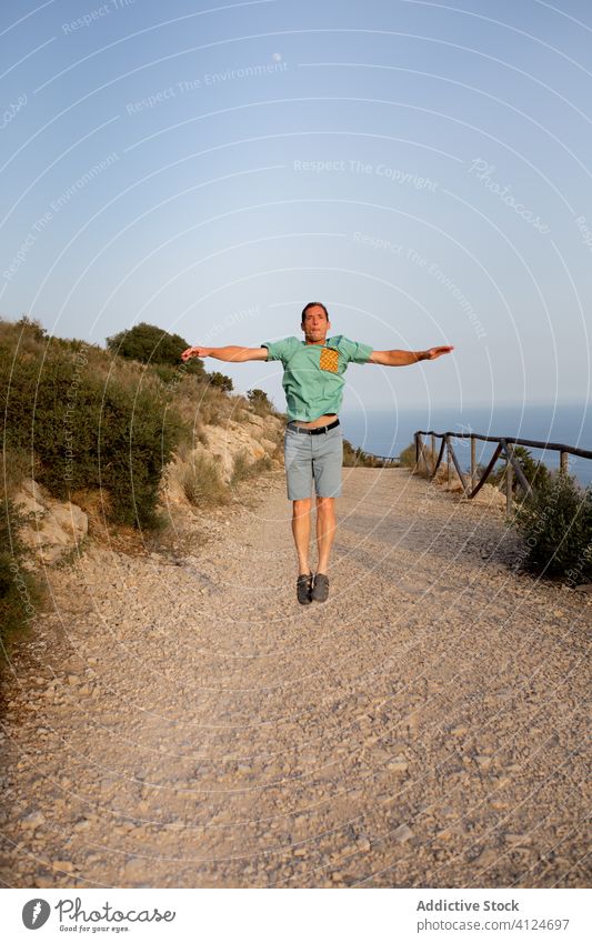 Man jumping on sandy sea coast man seaside happy freedom fly summer nature sky vacation holiday travel tourism enjoy male casual carefree shore fun energy