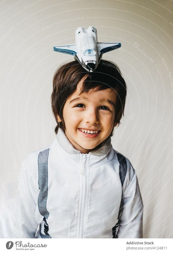 Adorable boy in cosmonaut costume on white background adorable spaceman toy spaceship positive child astronaut having fun kid spacesuit uniform smile cheerful