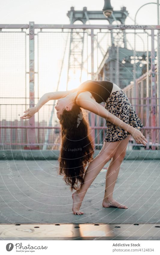 Slender flexible woman dancing on bridge in city dance grace back bend dancer slender barefoot female young casual skirt outfit wear perform show balance urban