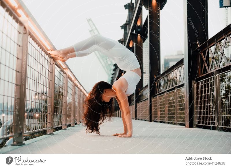 Fit woman practicing yoga on bridge urban handstand practice flexible asana scorpion handstand exercise fit back bend female city slim balance upside down pose