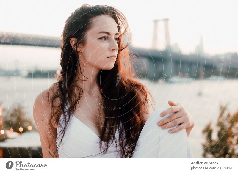 Charming woman enjoying cityscape in evening charming river bridge relax gorgeous female calm thoughtful pensive contemplate tender gentle long hair young