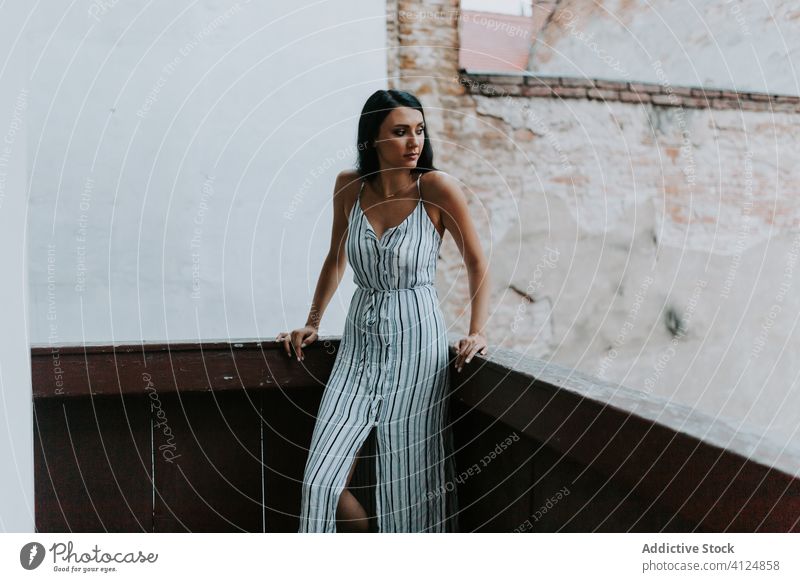 Young lady on balcony of old building woman rest shabby dress style young exterior female relax aged weathered terrace stripe serene architecture structure calm