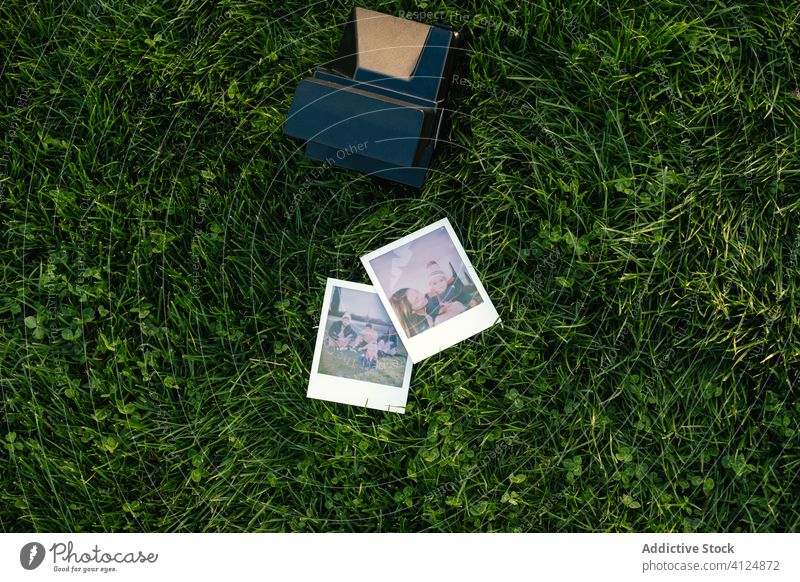 Instant camera and photos on green grass instant family picture park meadow love relationship kid child parent nature memory moment photography parenthood
