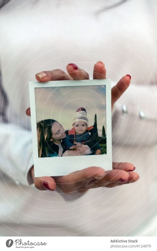 Anonymous woman showing picture of mother with kid photo happy love instant memory together young faceless anonymous female cute little street child parent