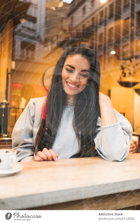 Cheerful young woman sitting in cafe cheerful trendy style enjoy coffee window female counter drink cozy cafeteria relax happy lifestyle city rest smile break