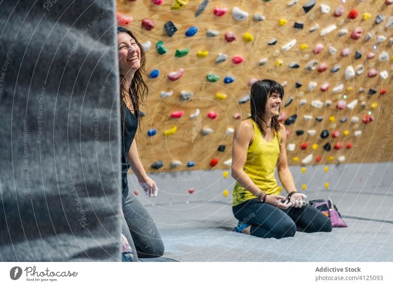 Content female climber resting after workout in gym woman sport smile training laugh enjoy sit wall grip relax equipment activity athlete energy lifestyle