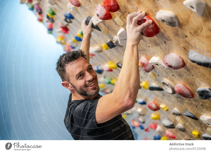 Man practicing climbing on wall man sport training boulder hobby equipment gym activity workout athlete extreme male exercise effort strength rock hang