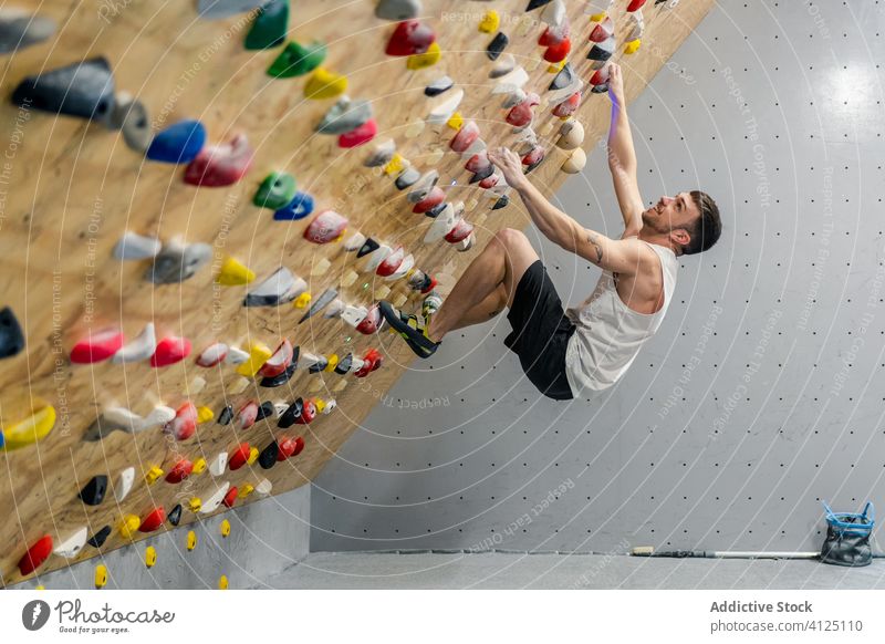 Man practicing climbing on wall man sport training boulder hobby equipment gym activity workout athlete extreme male exercise effort strength active rock hang