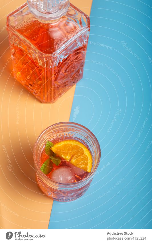 Glass of alcohol cocktail and bottle of rum glass refreshment ice mint orange cold cube slice sprig leaf green fruit ripe beverage drink crystal style elegant