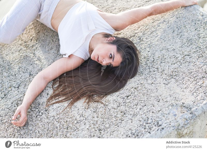 Young woman lying on stone construction near sea shore breakwater sensual dancer concrete contemporary concept modern allure body enjoy young female seaside