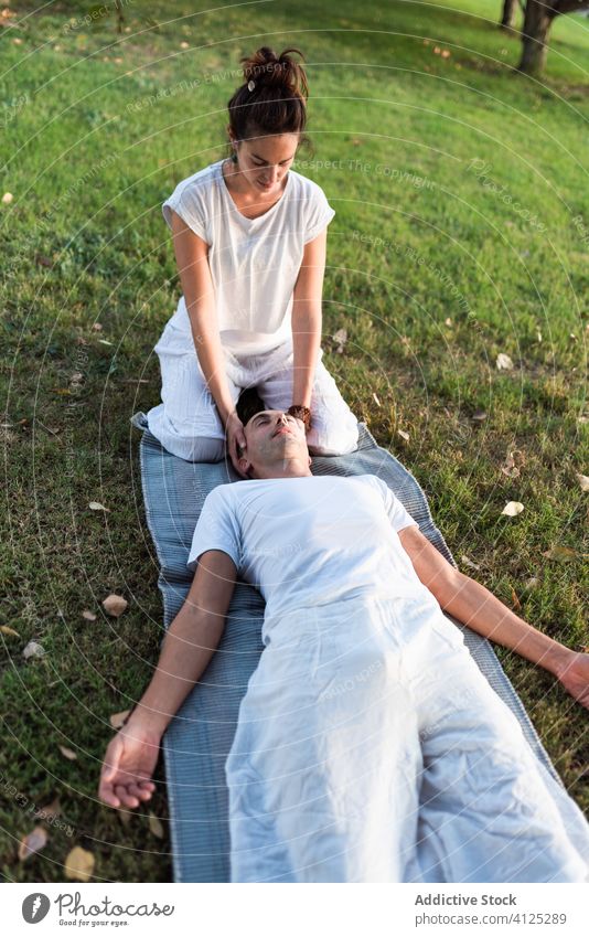 Relaxed couple meditating on green grass yoga meditate lying mat together eyes closed harmony meadow calm pose field spiritual massage white lawn summer tree