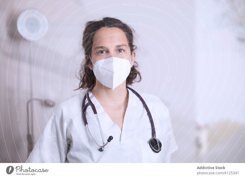 Positive young female doctor in medical mask standing in hospital woman uniform stethoscope clinic covid 19 coronavirus outbreak pandemic office positive