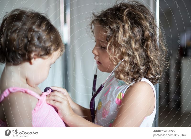 Little girl examining lungs of sister with stethoscope clinic children examine little visit hospital care doctor adorable kid together medicine patient sibling