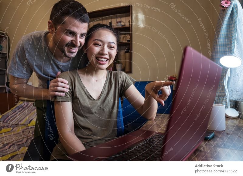 Couple of freelancers using laptop together at home couple project work help online happy multiracial smile multiethnic diverse asian self employed entrepreneur