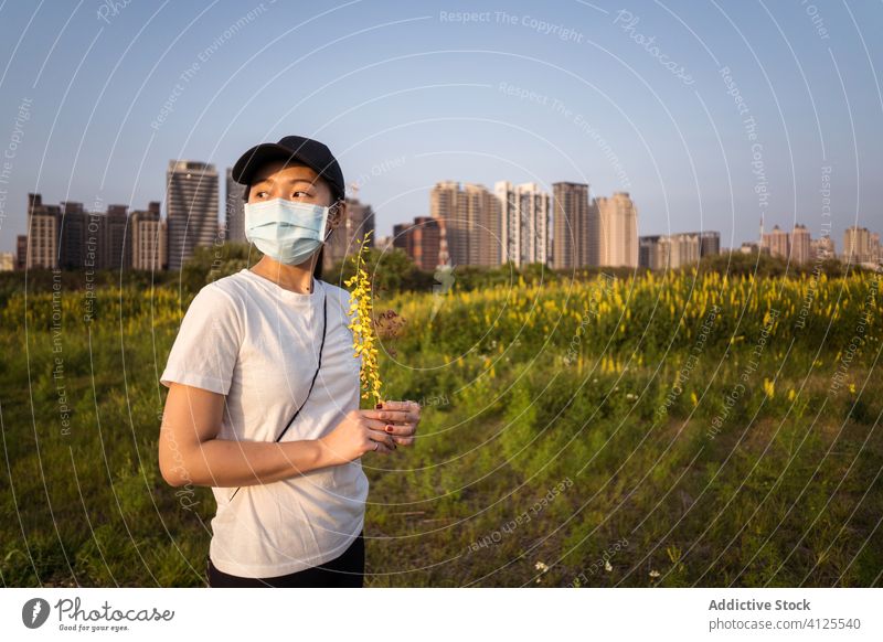 Ethnic woman in medical mask standing on green field protect coronavirus prevent covid nature young casual ethnic female modern safety health care covid 19