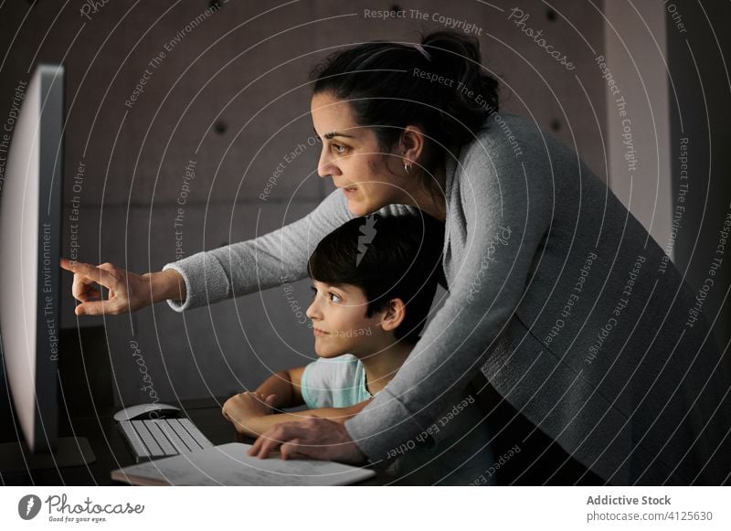 Mother helping kid with homework during online studies mother study education computer explain together child mom schooling son learn knowledge device gadget