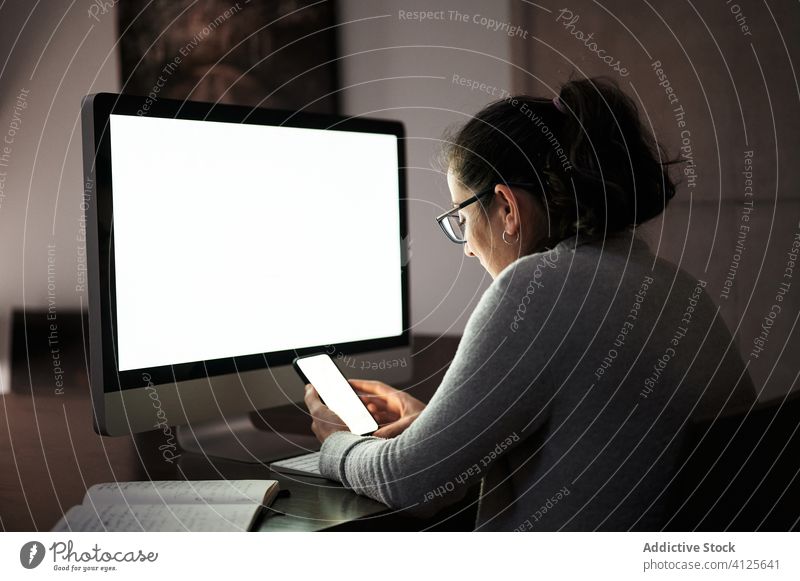 Focused woman working with gadgets at home smartphone computer telework using browsing young casual female serious concentrate focus blank screen empty screen