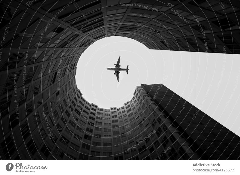 Aircraft flying over modern building in sky in city aircraft urban architecture round capture megapolis flight transport travel freedom contemporary exterior