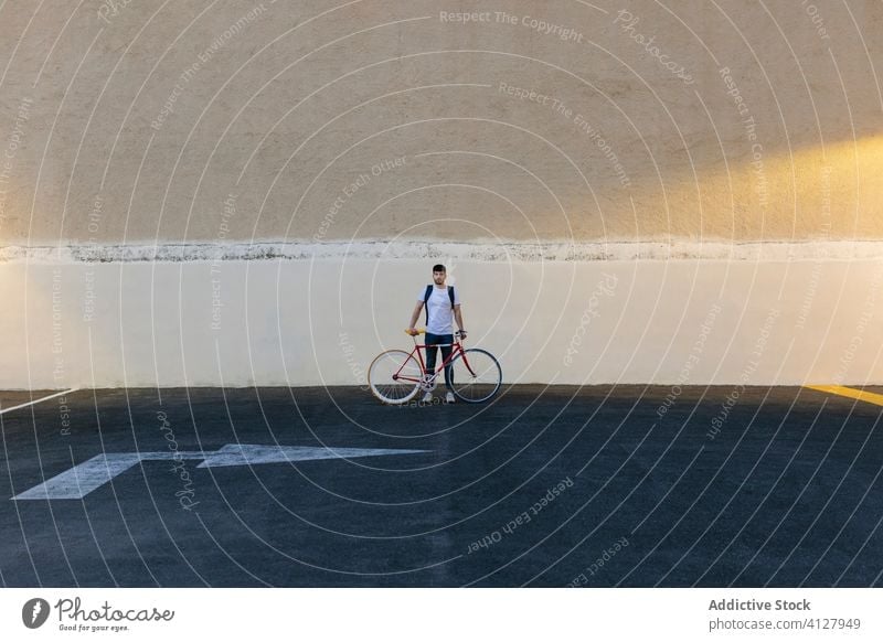 Man with a bike in the middle of a car park bicycle fixie urban wheel fixed sport transportation gear lifestyle wall street hipster ride pedal man biking chain