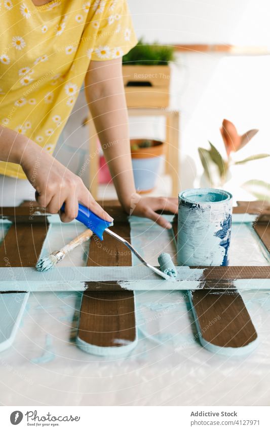 Unrecognizable woman painting a fence with light blue paint skill craft equipment brush caucasian construction craftswoman diy do it yourself female blonde