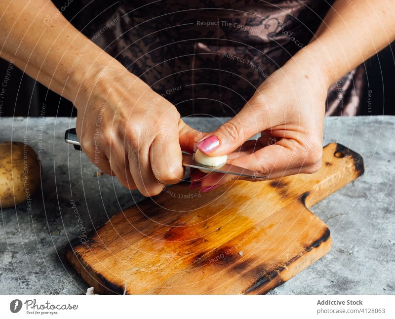 Crop woman cutting garlic in kitchen clove cutting board knife prepare cook female chopping board fresh table food uncooked cuisine culinary dinner nutrition