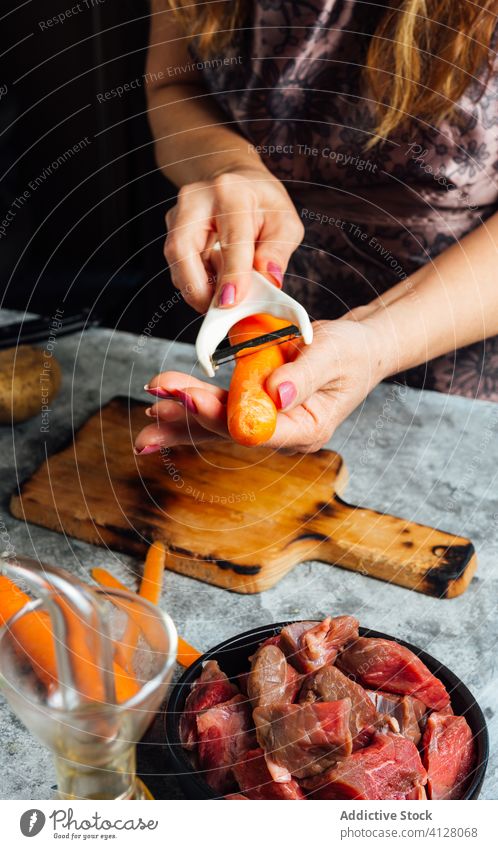 Female cook peeling fresh carrot in kitchen peeler woman cutting board vegetable prepare dinner female housewife chopping board food uncooked cuisine culinary