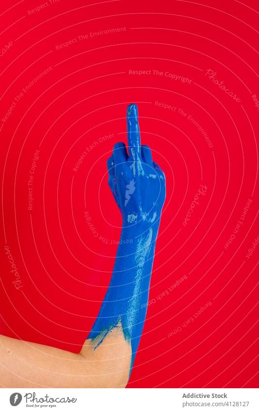 Crop person with middle finger in studio rude gesture paint sign show fuck aggressive colorful concept creative symbol gesticulate vibrant abstract vivid art