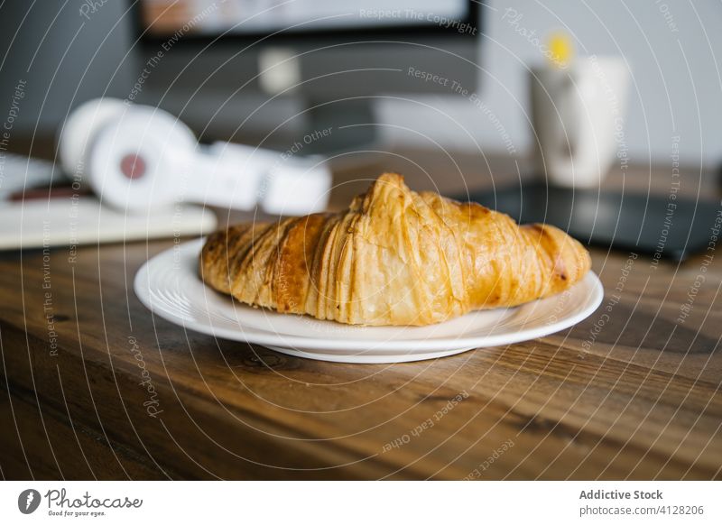 Croissant, notebook and headphones on workplace table croissant diary monitor morning breakfast telework plan planner cup plate wooden delicious tasty aromatic