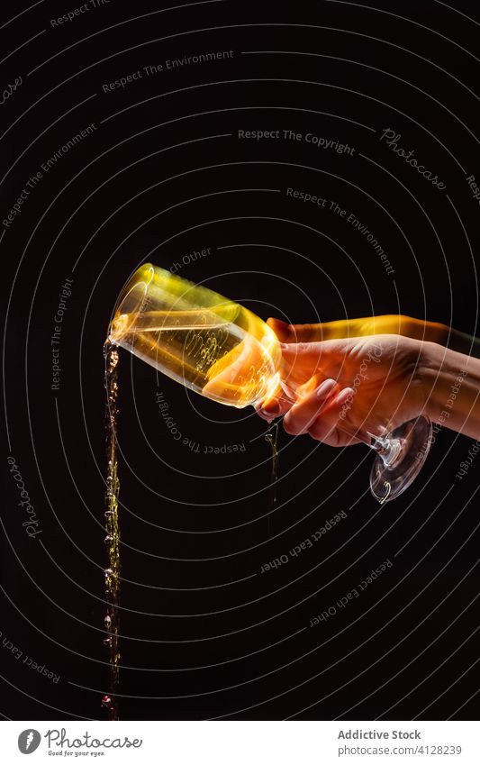 Crop anonymous person pouring drink from glass on black background hand alcohol hold party celebrate beverage fun champagne holiday entertain fresh tasty liquid