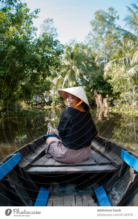 Traveling woman in boat during summer holiday travel river float smile tourist tropical female can tho vietnam asia conical hat cheerful delight content sit
