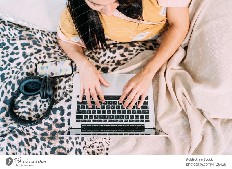 Woman with laptop and headphones on bed woman working typing music listen chill happy enjoy comfort lounge bedroom relax lifestyle rest gadget device home young