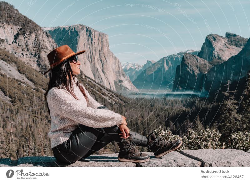 Happy woman enjoying sunny day in mountains travel happy relax forest yosemite park cliff edge sit rock stone national female style trendy landscape young