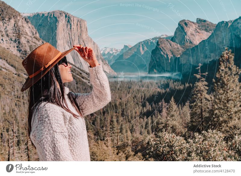 Happy woman enjoying sunny day in mountains travel happy relax forest yosemite park cliff edge sit rock stone national female style trendy landscape young