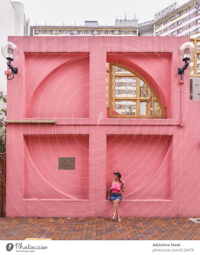 Woman near creative city installation in Hong Kong woman exterior district pink wall summer window shape unusual neighborhood female shek kip mei hong kong
