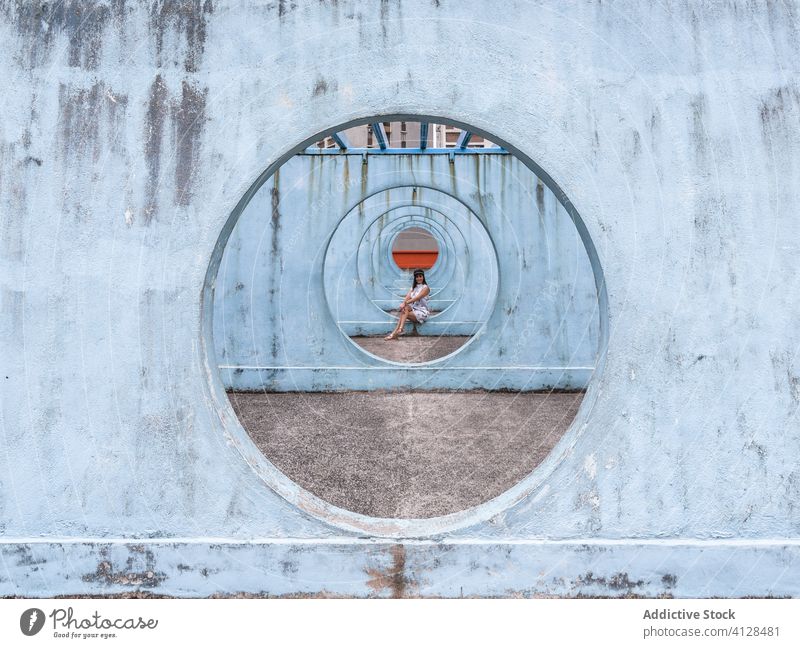 Woman sitting on walls with tunnel in Hong Kong woman passage street installation city unusual creative summer female shek kip mei hong kong round shape outfit