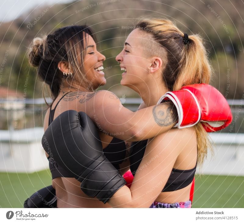 Cheerful female boxers in gloves embracing - a Royalty Free Stock