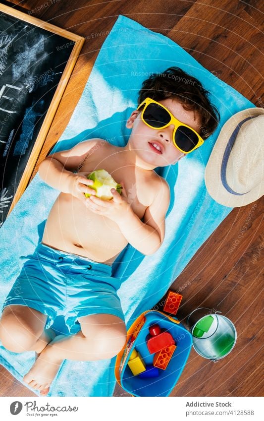 Happy little boy in sunglasses having beach at home dreaming of summer self isolation fun happy social distancing quarantine cheerful yellow blue playful
