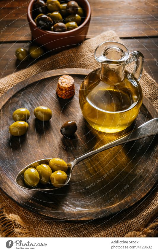 Oil in glass bottle and olives in spoon on table oil jar extra virgin wooden plate jug bowl kitchen decanter dishware kitchenware appetizer green cuisine