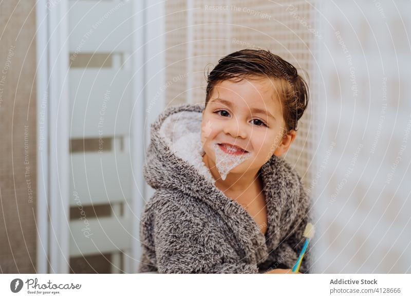 Little boy brushing teeth in bathroom toothbrush little child smile bathrobe kid oral hygiene wet hair cheerful soft cozy comfort cute home content delight