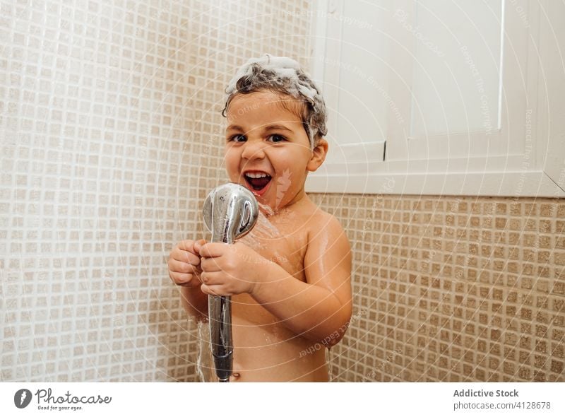 Cute boy singing in shower at home bathroom little foam smile child cute having fun kid cheerful content delight positive glad happy hygiene wet hair wash