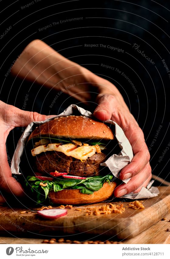 Anonymous person holding delicious vegan lentils burger gourmet hands lentil burger veggie burger fast food eating baked natural lifestyle organic spinach