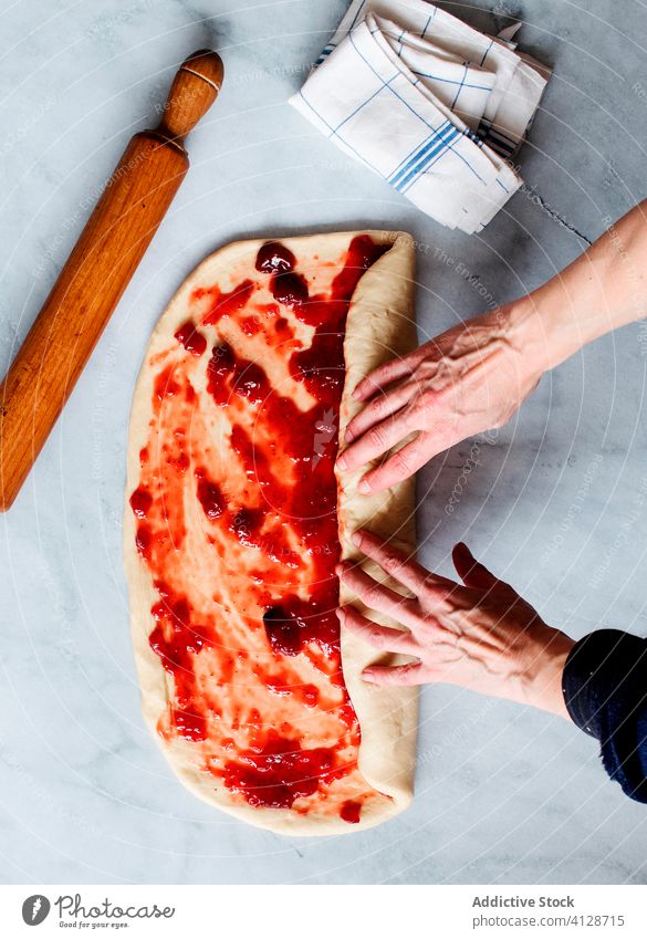 Anonymous person making fresh strawberry brioche on a marble table fruit preserve hands butter flour filling pastries sweet food sugar filled jam kitchen oven
