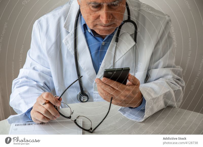 Senior male doctor consulting patient online during quarantine telemedicine man senior coronavirus smartphone video call using elderly aged gray hair general