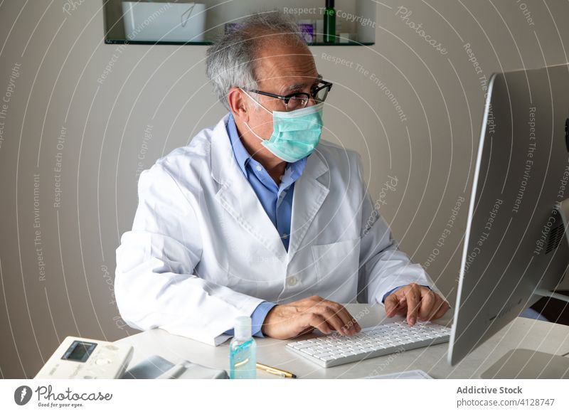 Elderly male physician conducting telemedicine consultation via laptop in clinic man elderly doctor telehealth outbreak using senior aged gray hair medical
