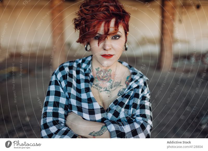 Confident tattooed woman looking at camera trendy independent informal style alternative confident young portrait modern street building female checkered shabby