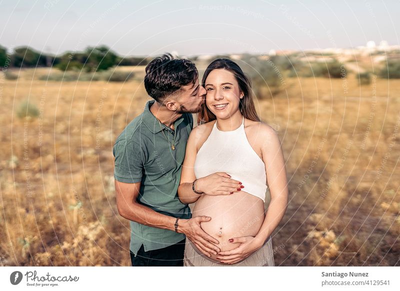 Young Pregnant Woman and her Husband pregnant relationship pregnant woman portrait kissing waiting looking at camera countryside happy smiling smile outside