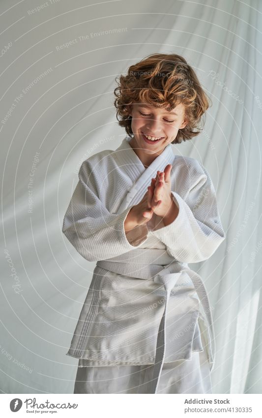 Positive young boy in white kimono practicing judo at home training belt martial studio determine smile confident sport positive childhood joy cheerful